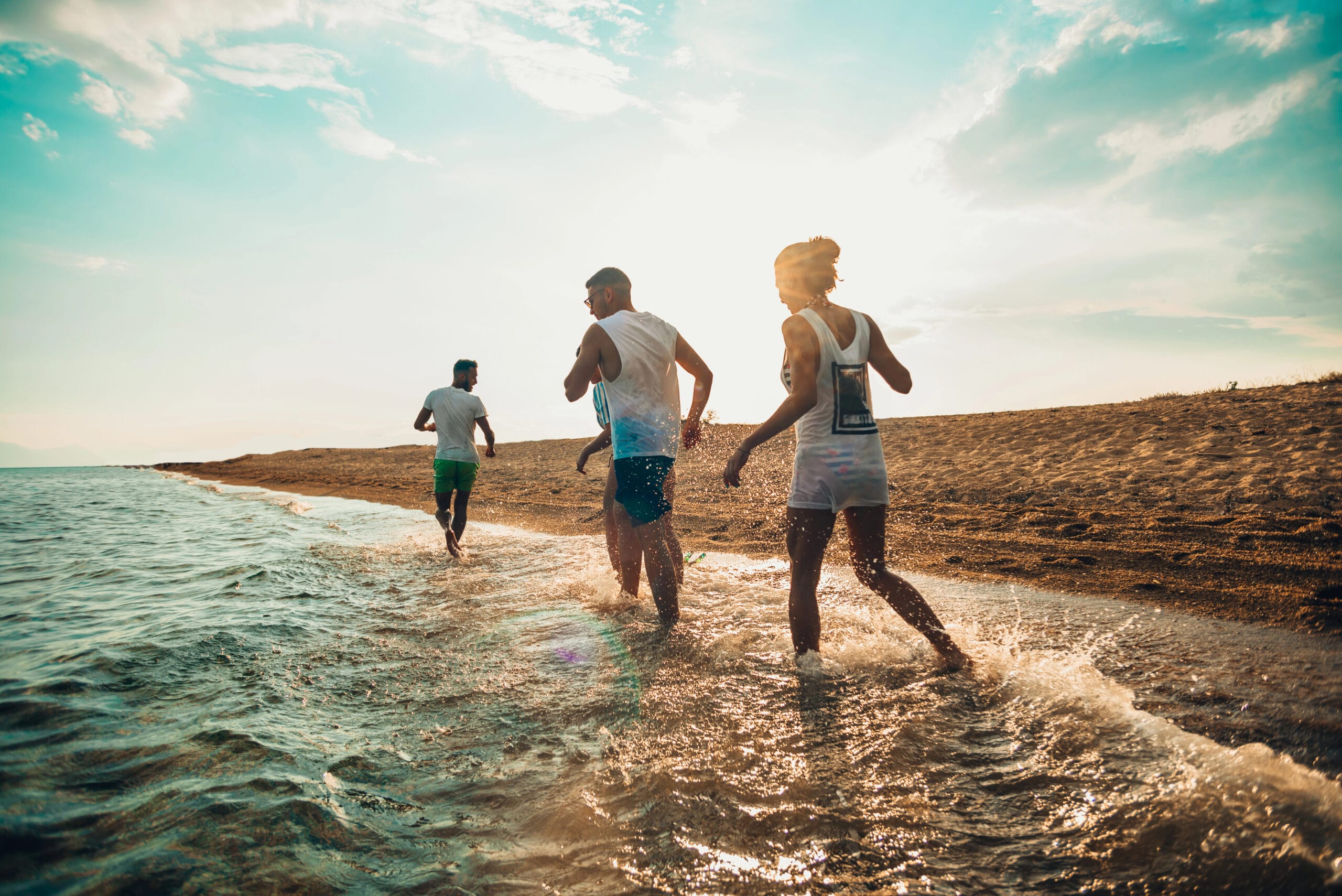 Family having fun walking in water along a beach.
