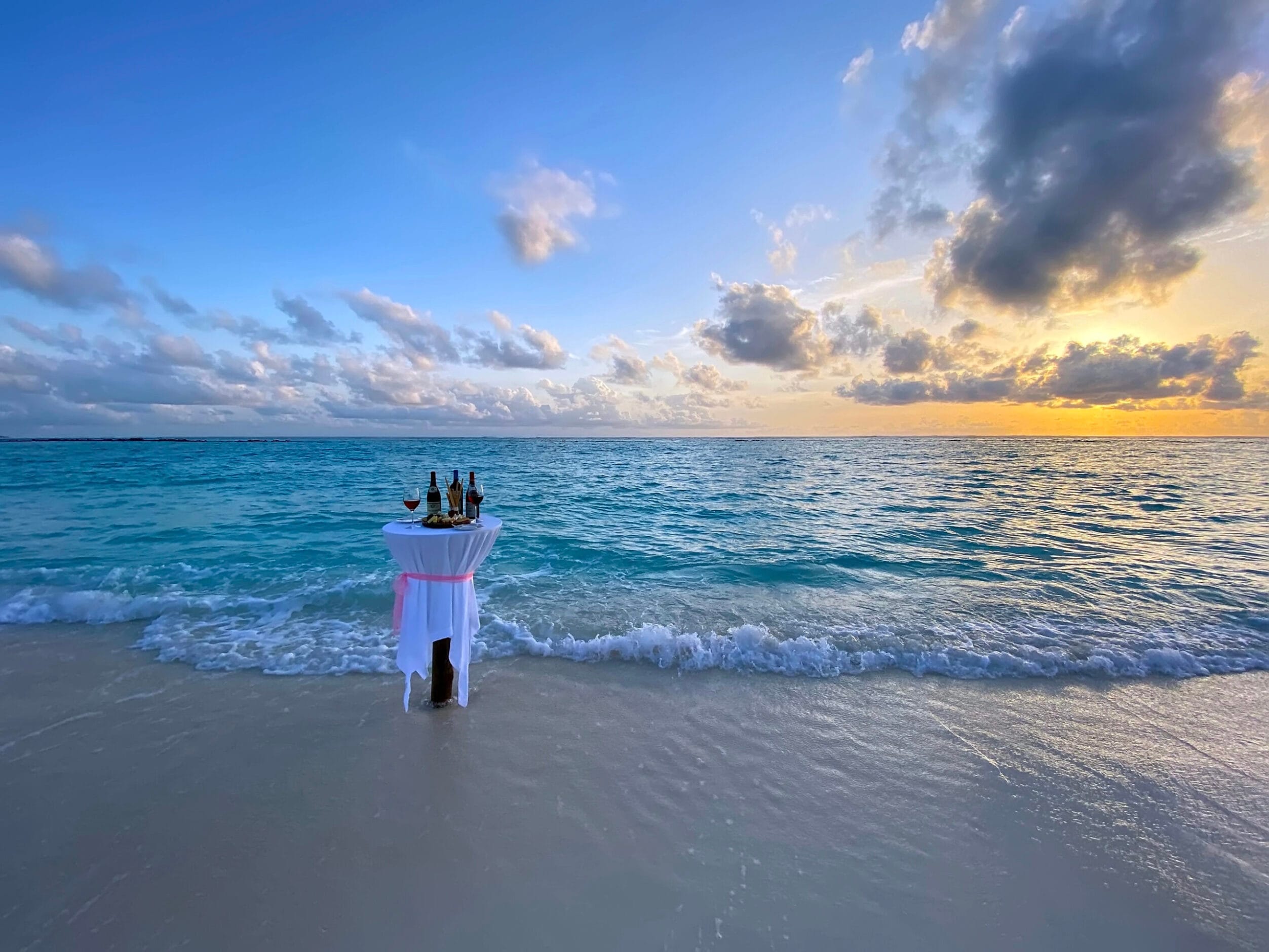 Honey Moon Celebration on Beach honeymoon destinations celebratiing on a beach with breaktaking view a table with a white cloth and champagne and glasses